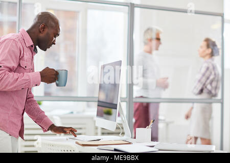 African casual businessman typing on computer while drinking coffee Stock Photo