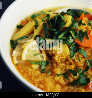 Red lentil stew with potato, carrot and turmeric. Close up. Healthy lunch on the round white plate. Colorful vegan dish with potato, carrot and turmer Stock Photo