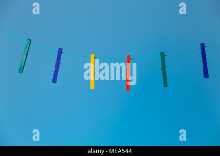 Group of clothes pegs on rope on blue background Stock Photo