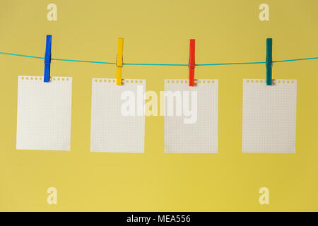 Schedule theme. Blank white paper lists pinned to rope with clothespins on yellow background. Stock Photo