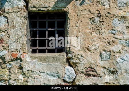 Old prison cell small window with metal bars and rock brick wall Stock Photo
