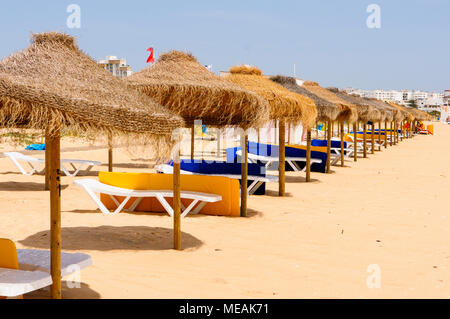 Rows of straw parasols and sunloungers on the beach at Vilamoura, Algarve, Portugal. Stock Photo