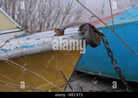 The iron boat is on the shore attached to a rusty castle with a chain Stock Photo