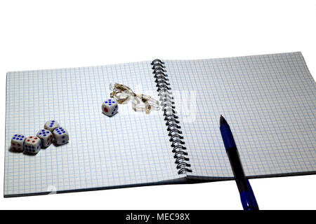 On an open notebook in a cage lie cubes, glasses and a pen Stock Photo