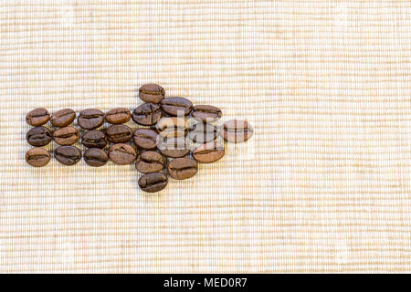 Coffee grains are lined in the form of an arrow on a beige napkin. A symbol of the correct direction. Stock Photo