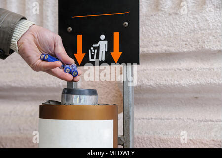 The man's hand is throwing used batteries in a container. Stock Photo
