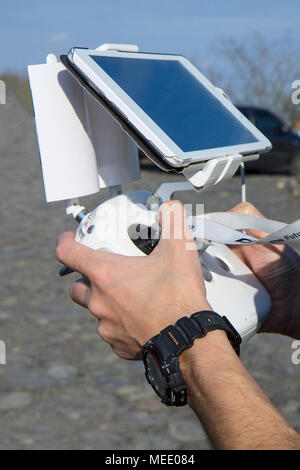 Man hands holding remote controller using tablet for drones flying. close-up on men hands of drone operator with a beautiful white remote control, vis Stock Photo
