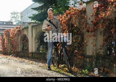 The man on the bicycle is looking at the screen of his smartphone. Stock Photo