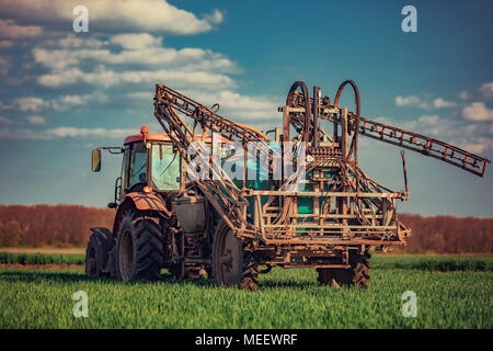 Farming tractor plowing and spraying on field Stock Photo