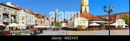 Bialystok, Poland - April 30, 2012: Town hall tower over red tile roof. Tourists walk on pavers central square of Kosciusko Market in Bialystok, Polan Stock Photo