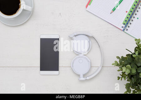 Office desk table layout with headphones and smartphone. Flat lay listening music composition on white wooden background Stock Photo