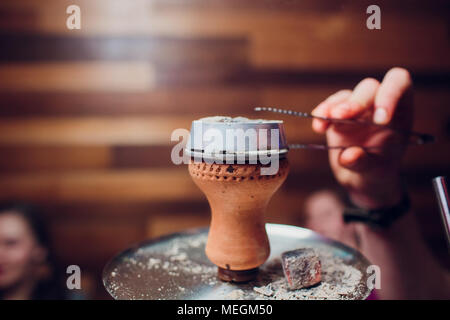 Preparing the shisha, aka nargile or hookah at a restaurant by placing the charcoals on top. Stock Photo