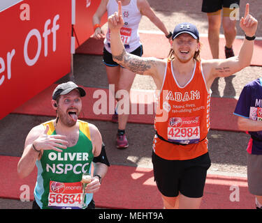 London, UK, 22nd April 2018. Runners celebrate as the cross the finish line. Record numbers of runners are taking part in the famous race - just over 47,000 registered and around 41,000 have picked up their race packs at the start. Despite many struggling with the with the hot and sunny weather along the route, the race is still expected to be on track to beat previous finish like numbers, too. Credit: Imageplotter News and Sports/Alamy Live News Stock Photo