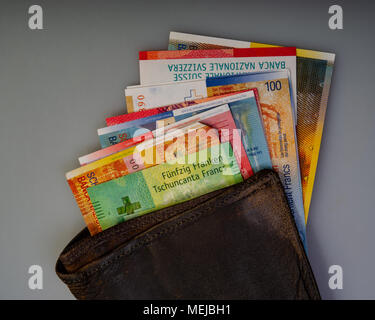 Swiss cash paper bills are in the old wallet. The purse with Switzerland francs lies on a light background. Stock Photo