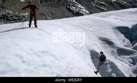one male mountain guide installing a pulley system for crevasse rescue on a glacier Stock Photo