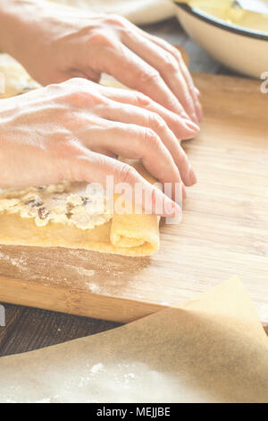 Woman is preparing a roll of dough with a cottage cheese filling Stock Photo