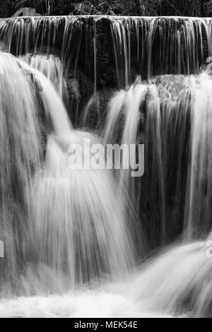 Full frame close-up of a cascade at the Tat Kuang Si Waterfalls near Luang Prabang in Laos. Natural abstract art in black and white. Stock Photo