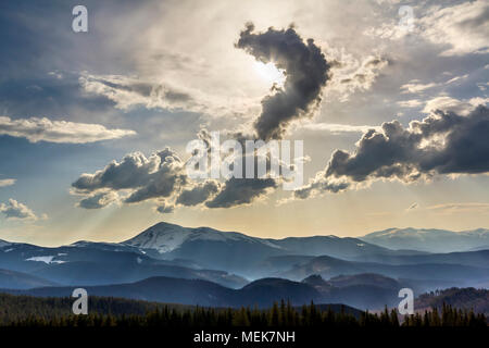 Beautiful fantastic view of blue sky with bright white clouds in mysterious shape of question over magnificent mountain rage with snow covered tops an Stock Photo