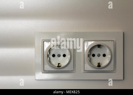 New white shiny plastic electric double sockets on white wall background. Advantages and comfort of modern homes. Stock Photo