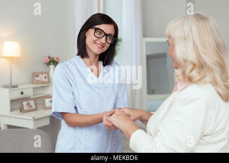 Jovial female caregiver providing help Stock Photo