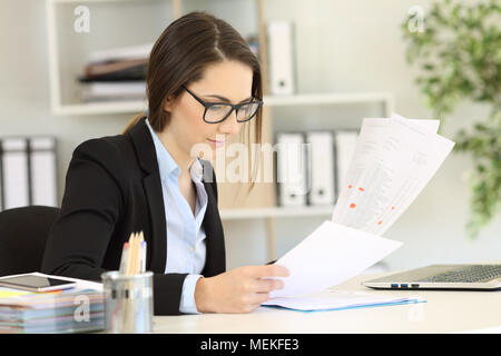 Office worker wearing eyeglasses checking paper documents Stock Photo