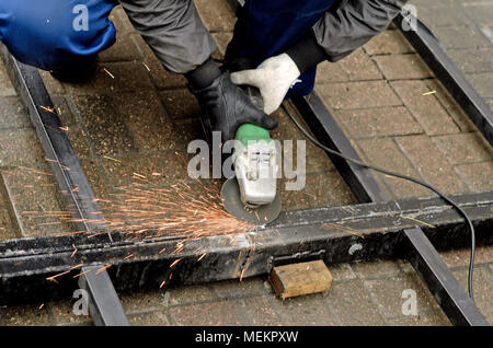 worker in gloves cleans the angle grinder metal construction. Stock Photo