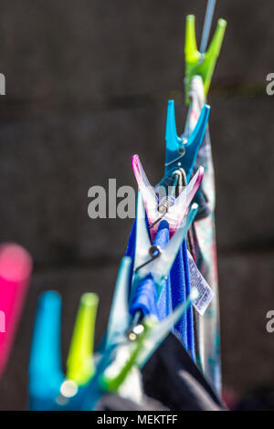 Plastic pegs on a washing line with clothes hanging from the line. Different coloured plastic pegs. Stock Photo