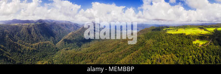 Aerial elevated panorama over Dorrigo national park main valley with mountains covered by Gondwana rainforest under blue sky on a sunny day. Stock Photo