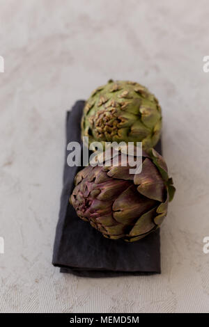 Artichokes on gray tabletop. Vertical composition. Shallow depth of field. Stock Photo