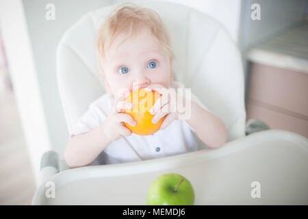 A baby boy in the kitchen eats fruit Stock Photo