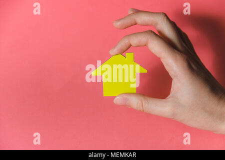 Female Hands Holding Yellow Paper House, Homeless Housing Shelter and Real Estate , Family House Insurance Concept Stock Photo