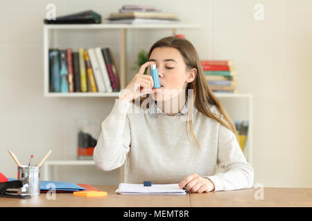 Student having an asthma attack using an asthma inhaler at home Stock Photo