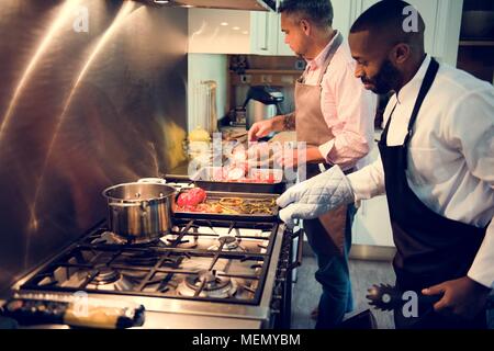 Two men cooking in a kitchen Stock Photo