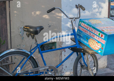 A blue delivery bicycle, with a large blue box for caring pizza mounted on the front, in San Miguel de Allende, Mexico Stock Photo