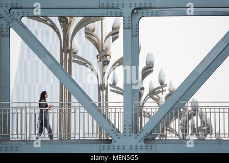 Chengdu, Sichuan Province, China - April 9, 2018 : Woman walking on a footpath bridge Stock Photo