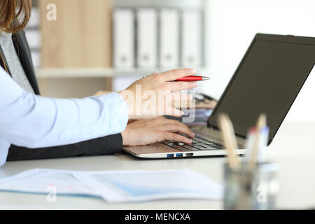 Side view close up portrait of two executive hands working online with a laptop on a desktop at office Stock Photo