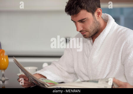 young freelancer in bathrobe working from home using tablet computer Stock Photo