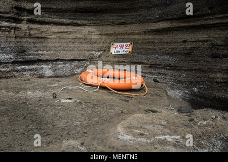 Orange life ring at the sandstone cliffs of Yongmeori Beach, Sanbang-ro, Jeju Island, South Korea Stock Photo