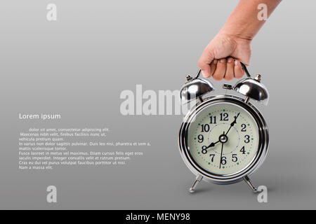 hand holding big classic alarm clock on gray background with left space for text, retro alarm clock at 8.30 AM Stock Photo