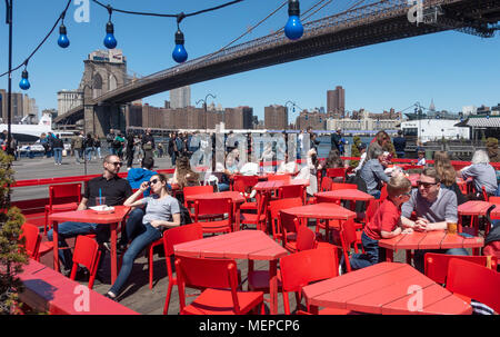 Tourists enjoying the sunshine and a beverage at alfresco tables in Dumbo, Brooklyn Stock Photo