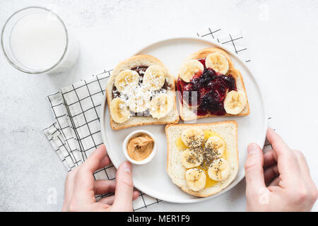 Vegan nut butter toasts with different toppings. Chia seed, raw jam, banana and coconut. Vegetarian, healthy lifestyle, trendy modern snack concept Stock Photo