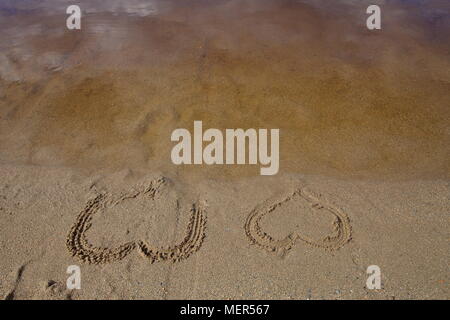 . Two hearts are drawn in the wet sand of a beach Stock Photo
