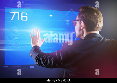 Attentive programmer carefully touching the screen of his futuristic computer Stock Photo