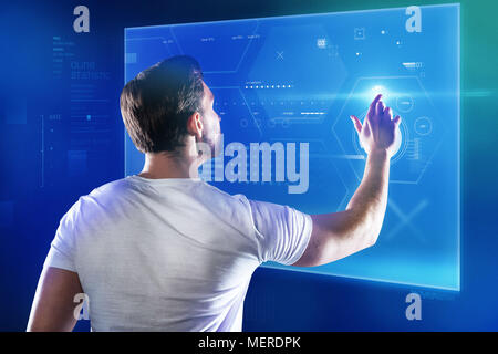 Skilled programmer working with a new device and touching a transparent screen Stock Photo