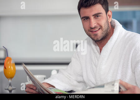 young freelancer in bathrobe working from home using tablet computer Stock Photo