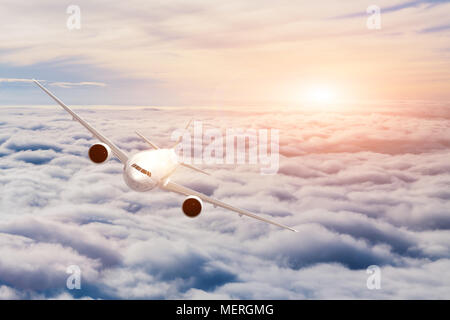 Airplane in cruise flight above the clouds. Beautiful sky, sunset light and reflection on the flying aircraft. Concept about air travel Stock Photo