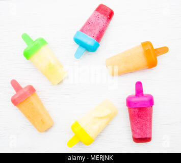 A flat lay image of colourful, frozen fruit smoothie ice lollipops on a white background Stock Photo