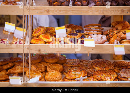 Showcase of a bakery with fresh pastries: pizza, buns with berries and poppy seeds, pie with meat Stock Photo