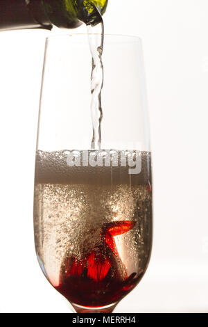 Pouring sparkling white wine over Hibiscus flower in glass Stock Photo