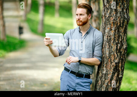 Businessman using tablet pc in nature Stock Photo